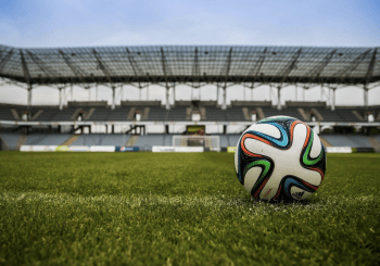 Photo of football field, football in foregrouns, for article topic - Is the culture of online betting dangerous