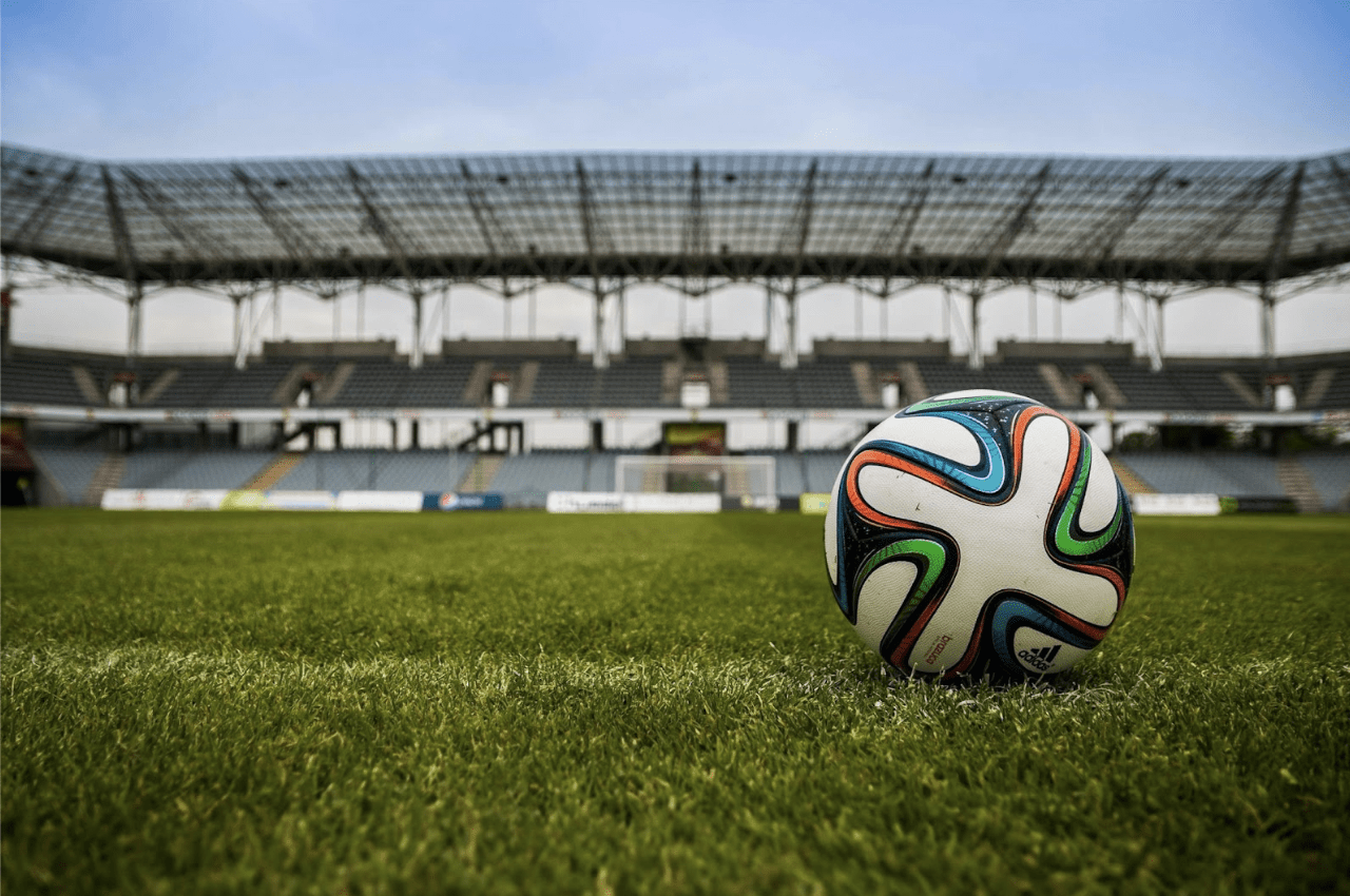 Photo of football field, football in foregrouns, for article topic - Is the culture of online betting dangerous