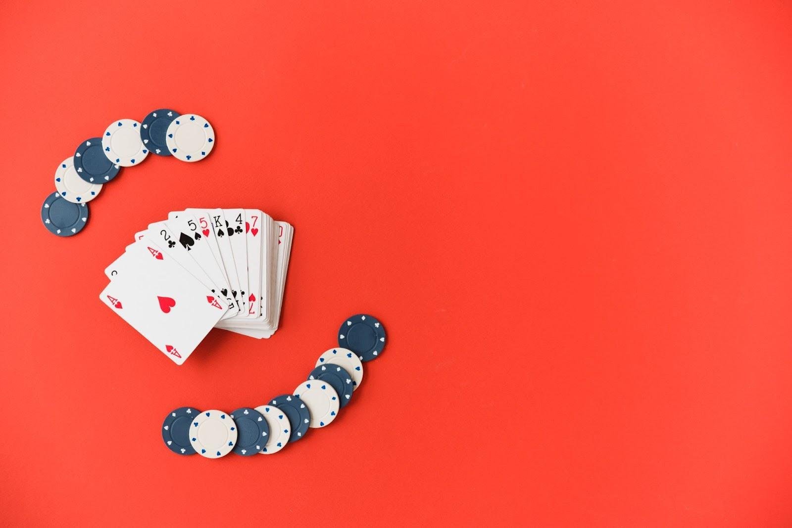 Red background, playing cards and poker chips placed to the left to illustration a story titled The Types of Card Games You Will Find in Casinos
